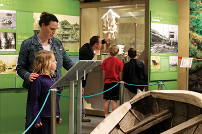 mother and child reading sign next to a boat in the coos history museum