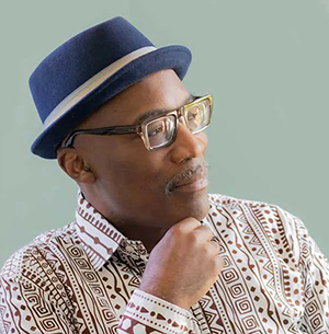 Musician Darrell Grant wearing African inspired shirt and blue hat.